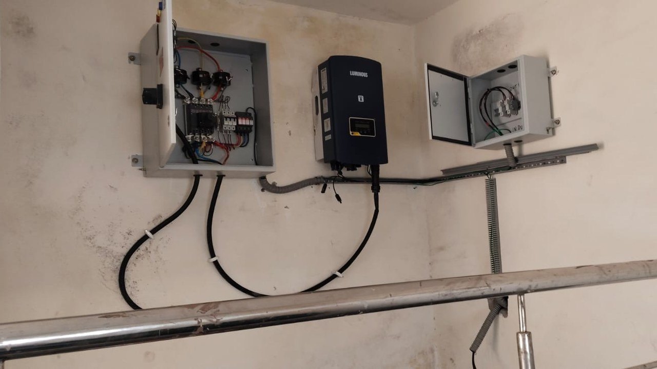 Efab AC and DC distribution boxes opened to show breakers and surge protection, beside a Luminous inverter at an AIIMS New Delhi hostel