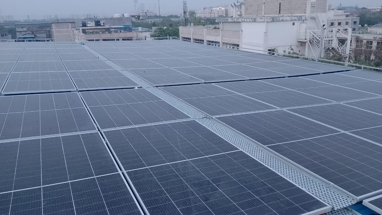 70 kW Trina solar array on the raised steel shed above Arihant Cold Storage, Okhla Phase II, New Delhi, with a cable tray walkway between the rows