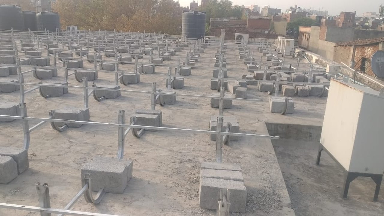 Concrete ballast blocks holding the solar mounting structure on the old roof slab at Liberal Traders, Okhla, with no drilling into the roof
