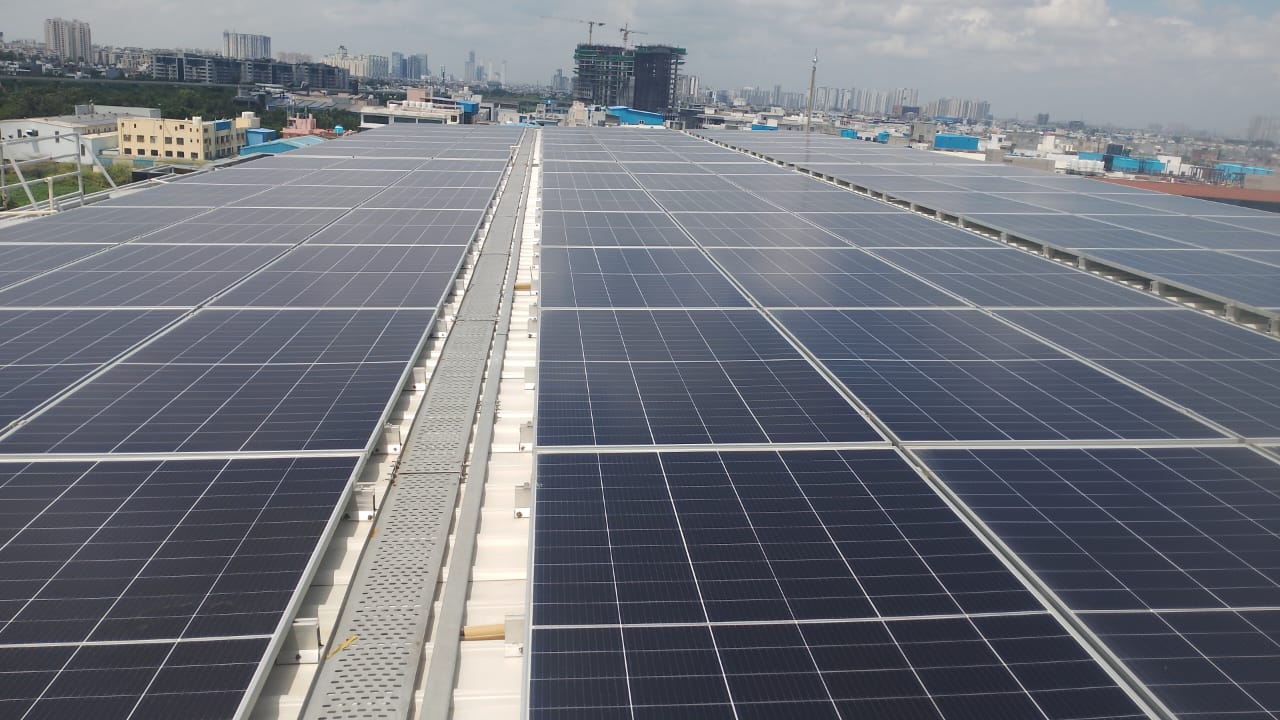 85 kWp rooftop solar array on the raised steel shed at Steadfast Limited, Sector 85, Noida, with a central cable tray walkway